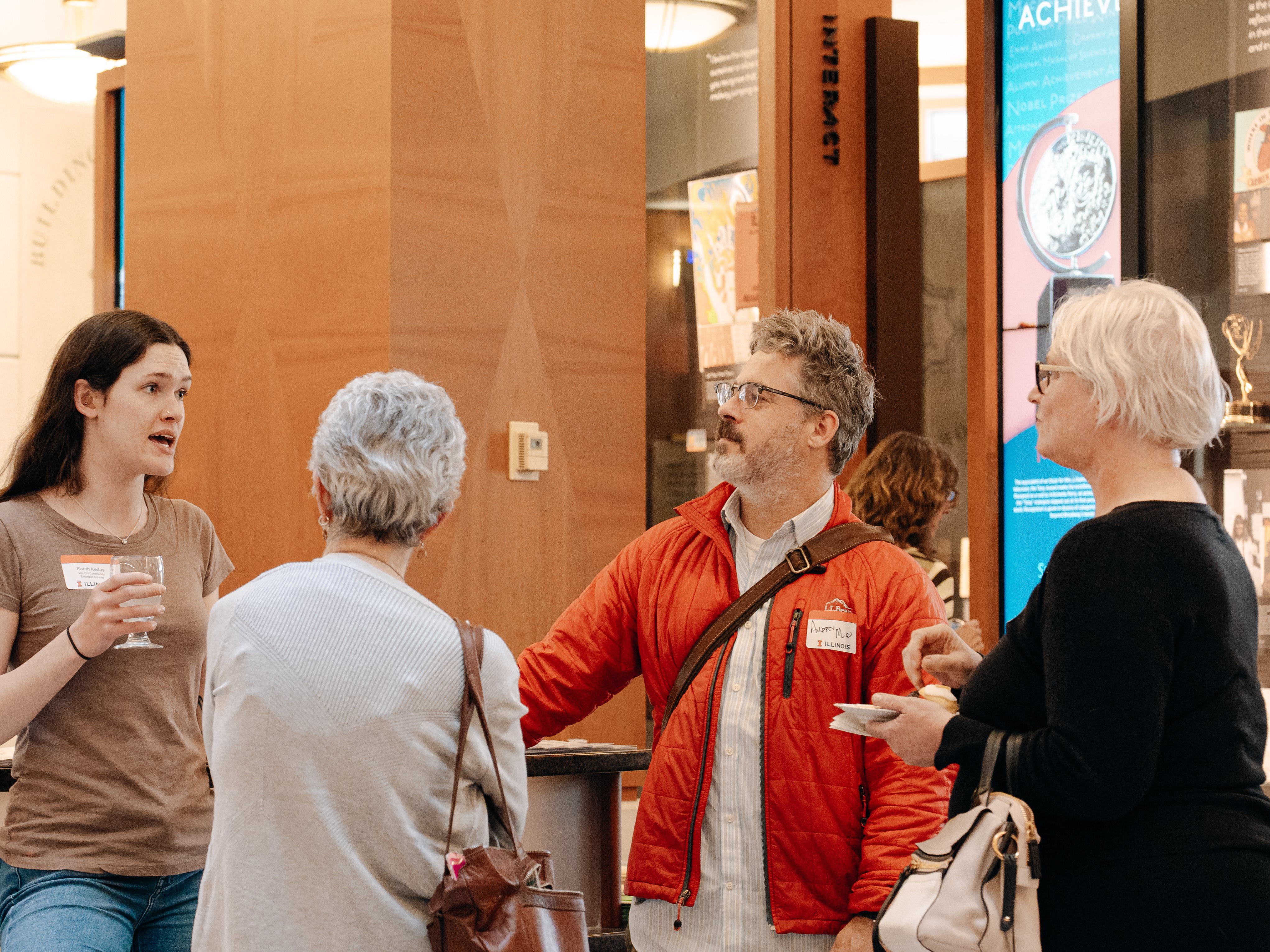 Instructor Andrew Moss  chats with 3 attendees at We CU's Spring Reception.